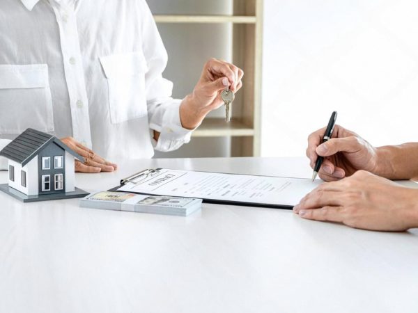 Real estate agent handing over keys and signing a Dubai property insurance contract